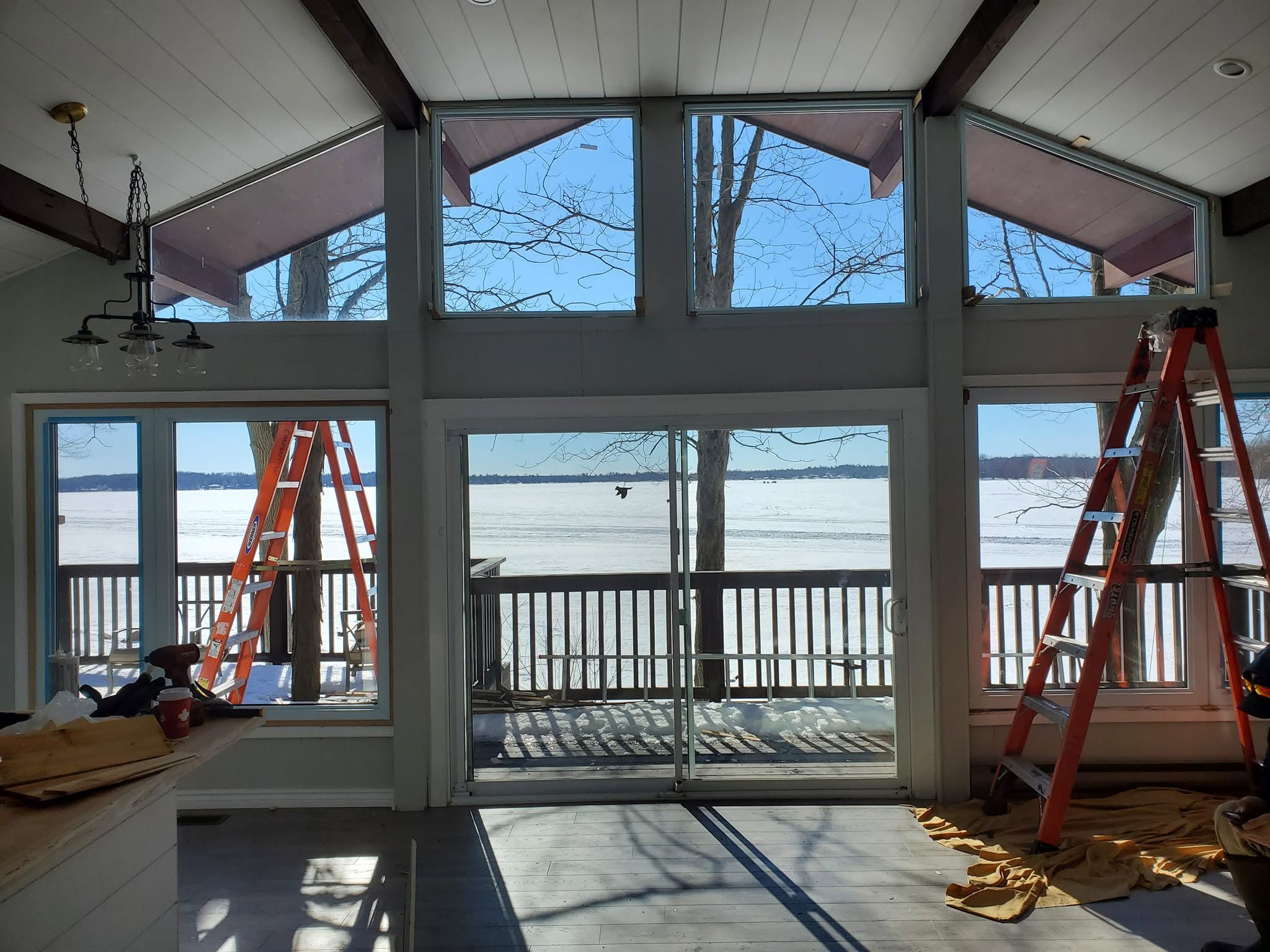 Lakefront cottage interior with sliding glass patio doors and surrounding windows during installation
