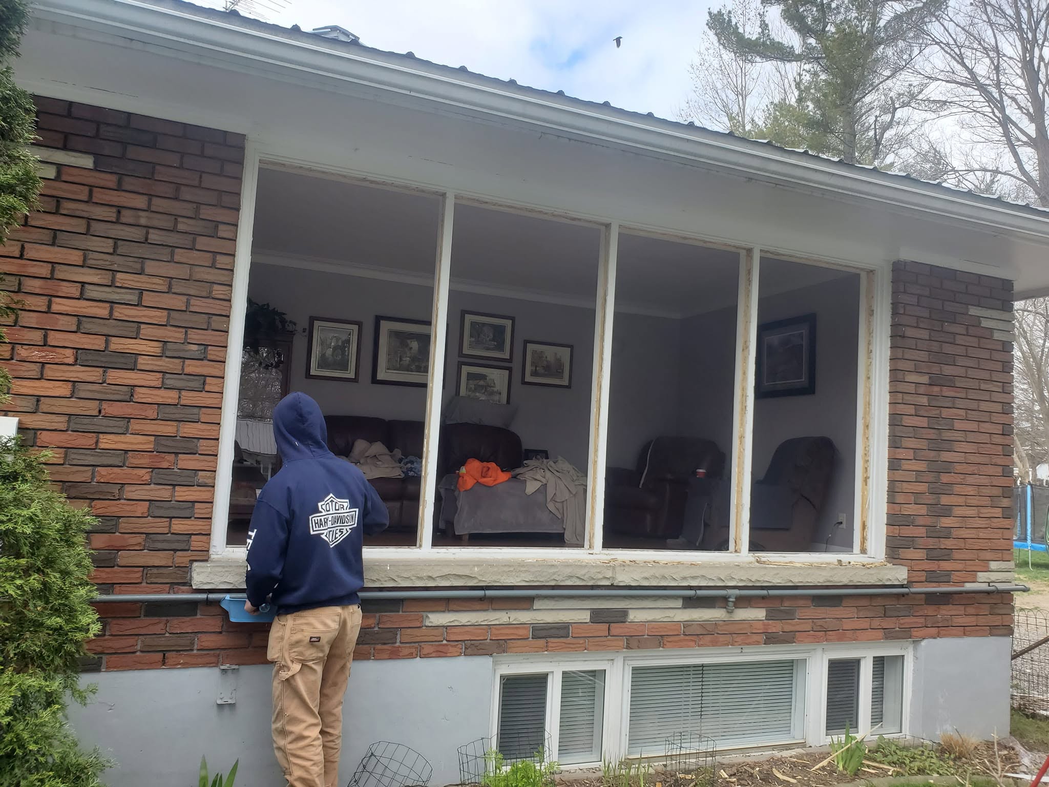 Window replacement work in progress on a brick cottage exterior