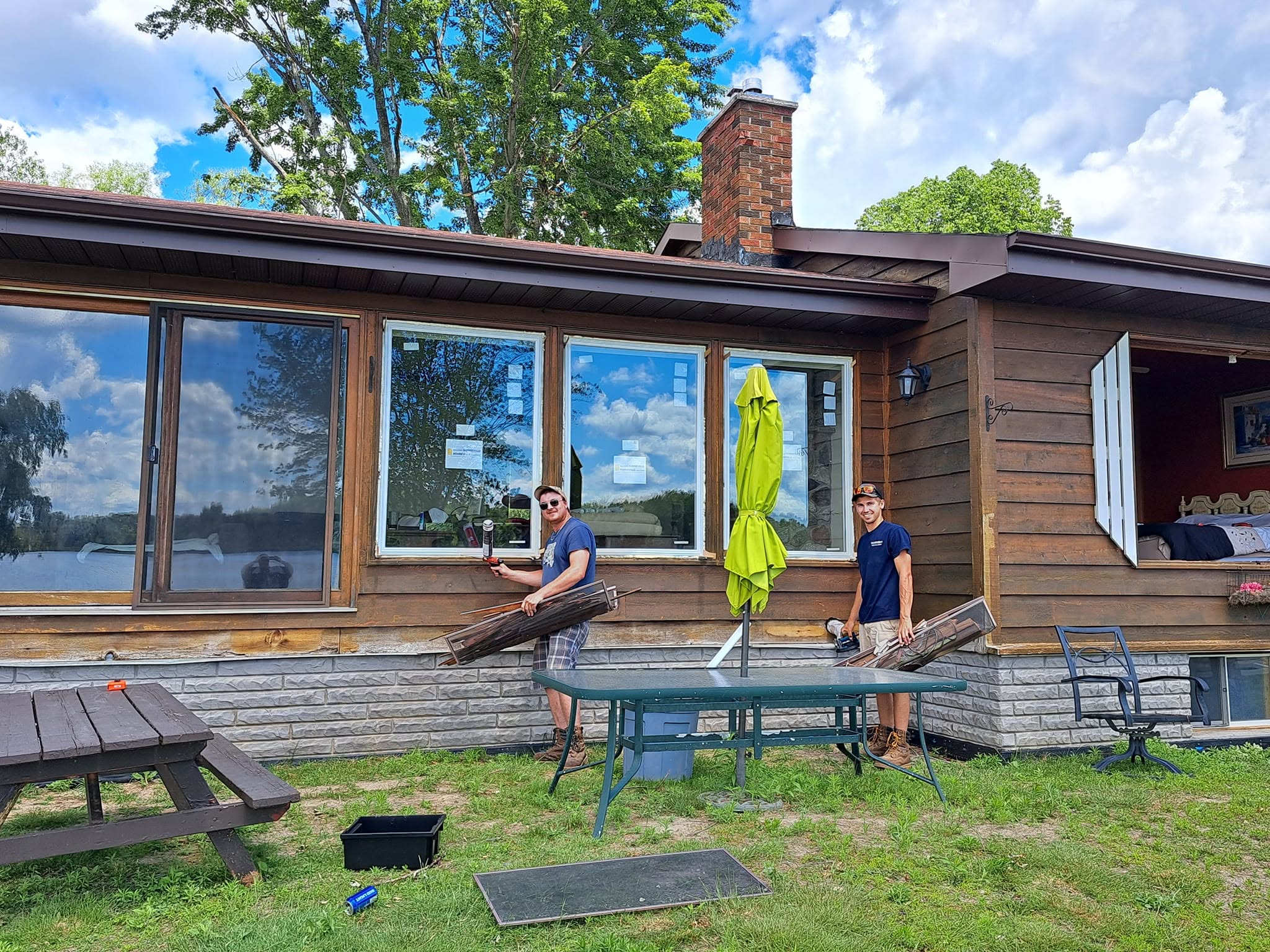 Terrion crew installing replacement windows at a wood-sided lakefront cottage